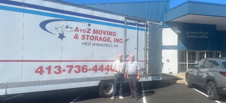 Moving truck for A to Z Moving & Storage parked outside a storage unit, with two people standing beside it.