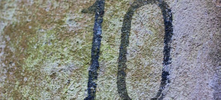 Close-up of a weathered stone surface with the black number 10 painted on it.