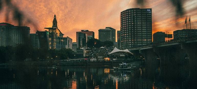 City skyline at sunset with orange clouds reflected in a calm river