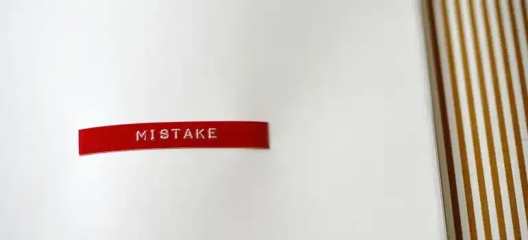 Red label reading “MISTAKE” on a white page next to brown striped binding.