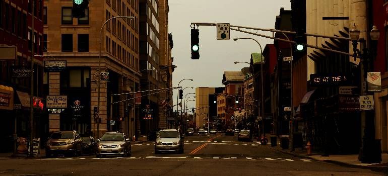 Downtown street with cars at a traffic light between tall buildings in warm, dim light