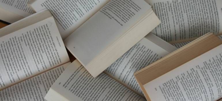Scattered open books with pages visible, forming a layered reading scene.