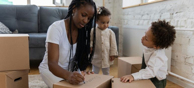 Woman packing boxes with two children in a living room