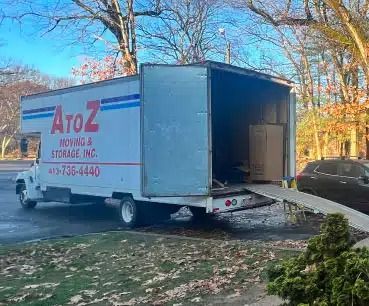 White AtoZ moving truck parked at a curb with the rear ramp lowered on a residential street