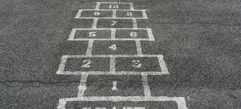 Painted hopscotch grid on asphalt pavement, numbered white squares receding into the distance.