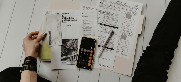 Hands sorting bills and receipts beside a calculator on a desk