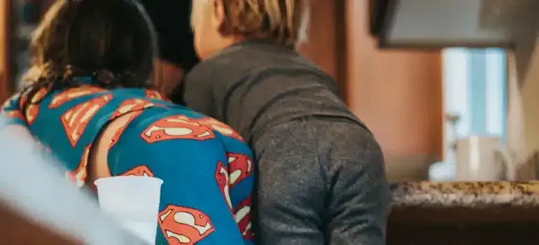 Two people sitting at a kitchen counter, one in a blue Superman shirt.