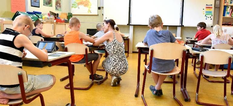 People seated at tables in a bright classroom, writing and talking during a group activity