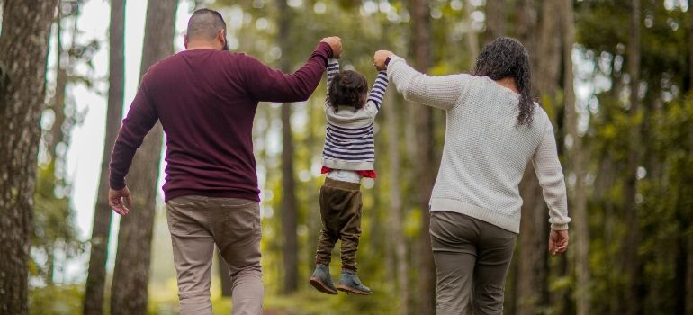 Family walking hand in hand on a forest trail, seen from behind