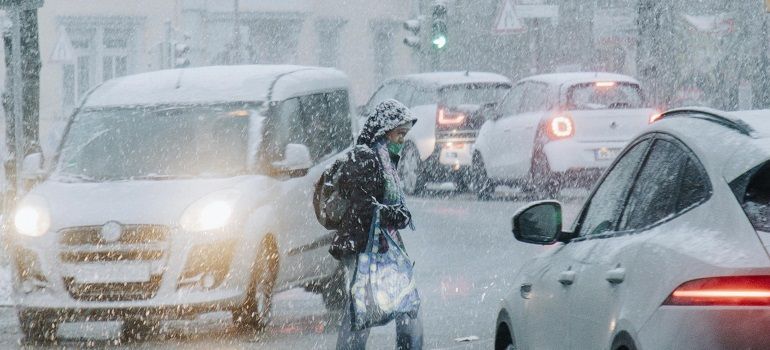 Snowy traffic jam with cars and a pedestrian crossing in heavy snow