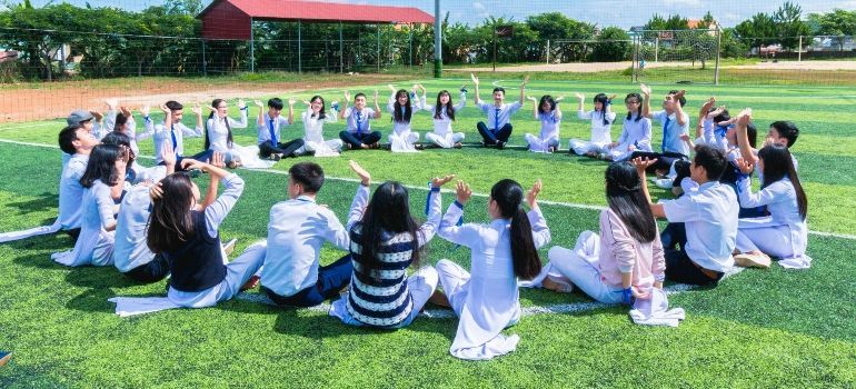 People sitting in a circle on grass outdoors, appearing to hold a group exercise or discussion
