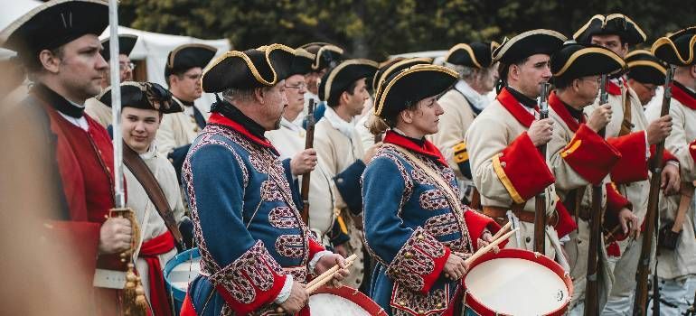 People in traditional embroidered uniforms playing drums and brass instruments in a street parade