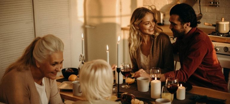 Friends gathered around a candlelit table, smiling and talking in a cozy room.