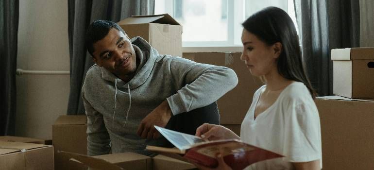 Two people sit on a couch, reviewing papers together in a living room.