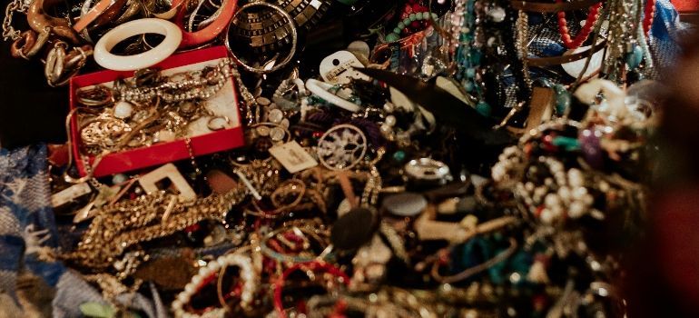 Assorted gold and red jewelry, beads, and trinkets scattered in a cluttered close-up.