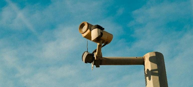 Two beige security cameras mounted on a pole against a blue sky