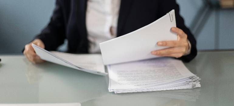 Person in a business suit flipping through a stack of papers at a desk
