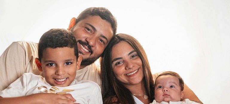 Smiling family of four posing closely together against a white background