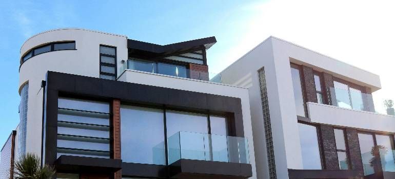 Modern multi-story house with curved white facade and dark wood accents under a blue sky