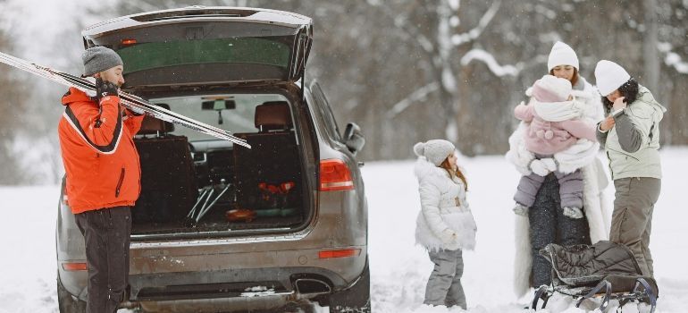 Family loading gear into an SUV in a snowy parking lot