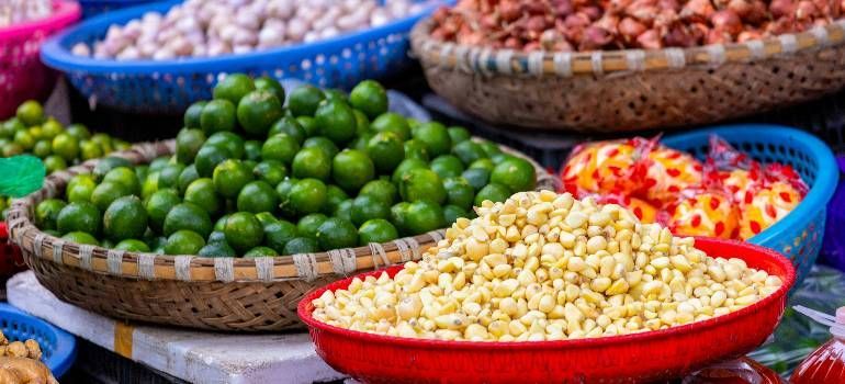 Colorful baskets of fresh fruits at a market, including green limes and yellow grapes.
