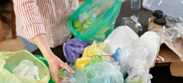Person sorting colorful plastic bags for recycling indoors