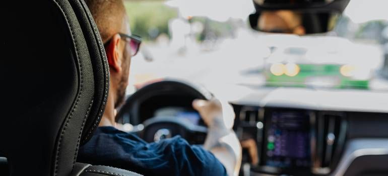 Driver’s view from the back seat, hands on steering wheel in a moving car