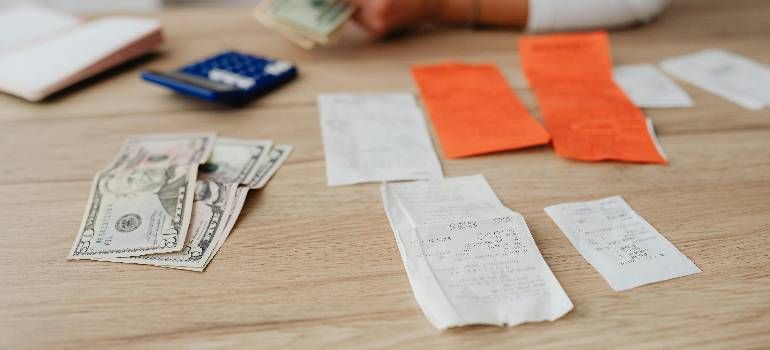 Cash and receipts laid out on a wooden table with orange and white paper slips
