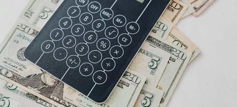 Calculator on scattered paper currency banknotes, suggesting budgeting or financial calculations.