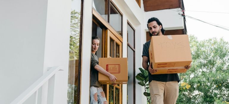Two movers carrying boxes into a home through the front door