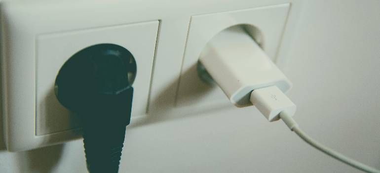Two wall outlets with black and white plugs inserted, one cord trailing right
