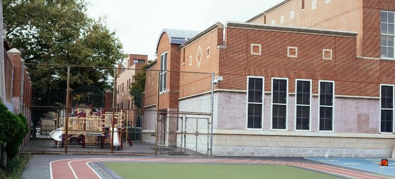 School building with brick walls, tall windows, and a running track in the foreground