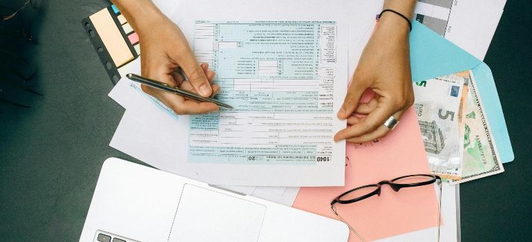 Hands reviewing paperwork on a desk with a calculator, pen, and ID card.