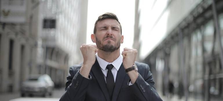 Businessman in a suit clenching his fists in a city street, looking frustrated or determined