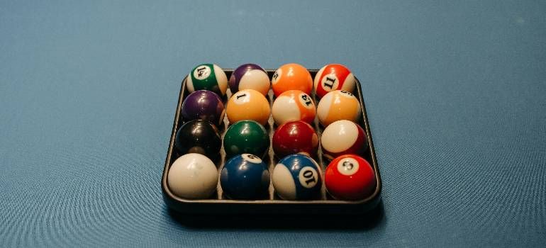 Racked billiard balls in a black tray on a blue cloth surface
