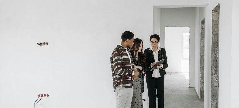 Three people reviewing documents in a bright, empty room under renovation