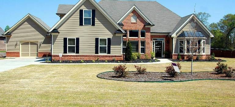 Suburban brick-and-siding house with a front lawn, driveway, and landscaped yard