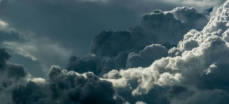 Dark storm clouds billow over a mountainous horizon