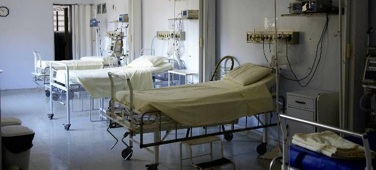 Hospital room with two empty beds, medical equipment, and white curtains