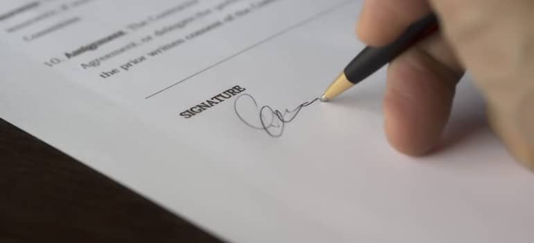 Hand signing a document with a pen on a white page
