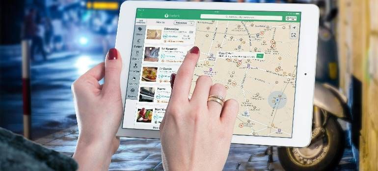 Hands using a tablet with a map and listings while walking outdoors at night