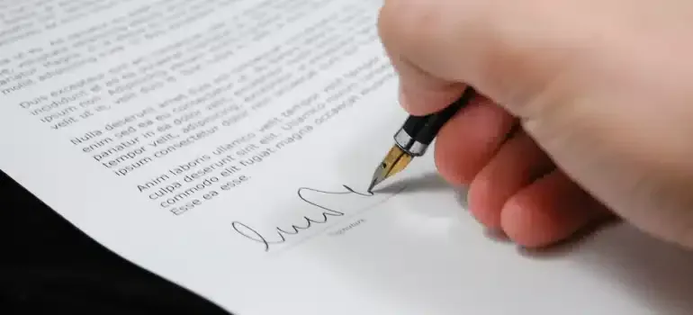 Hand signing a document with a pen on white paper