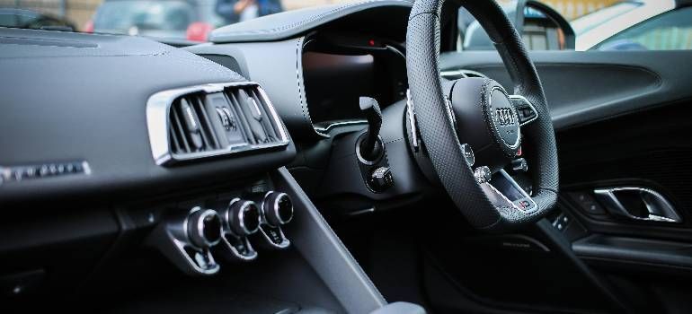 Close-up of a luxury car interior with black leather seats, steering wheel, and chrome dashboard vents