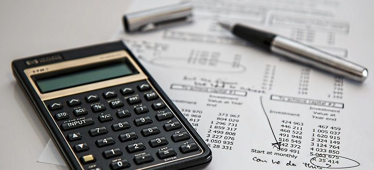 Calculator on financial paperwork with a pen and glasses on a desk