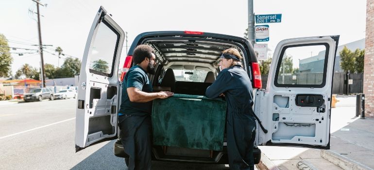 Two people unloading a stretcher from an ambulance at a street curb