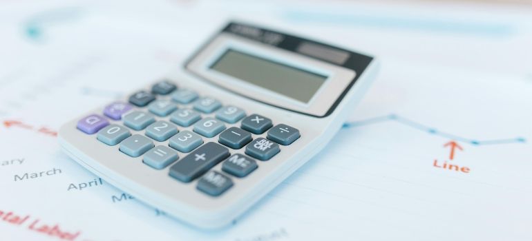 White calculator on a financial chart with blue keys and a blank display