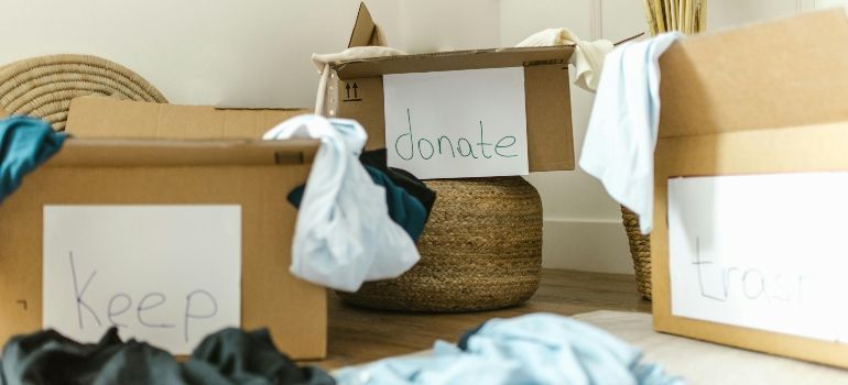 Cardboard donation boxes labeled keep, donate, and maybe with folded clothes around them