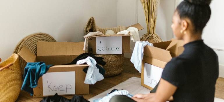 Person packing labeled boxes in a home office with baskets and fabric items