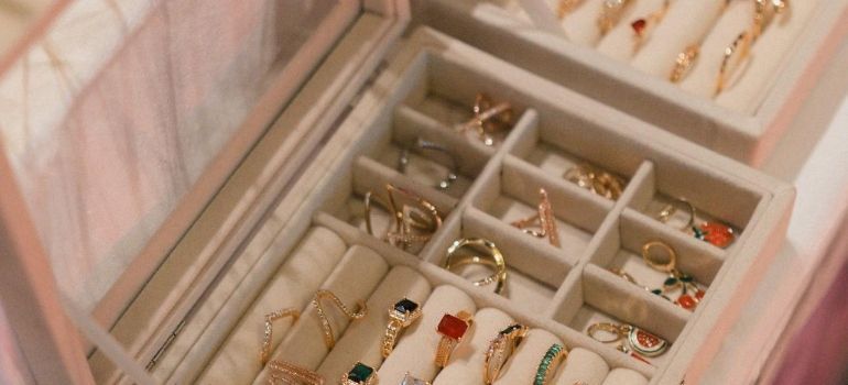 Open jewelry box with assorted gold and gemstone rings and bracelets in compartments