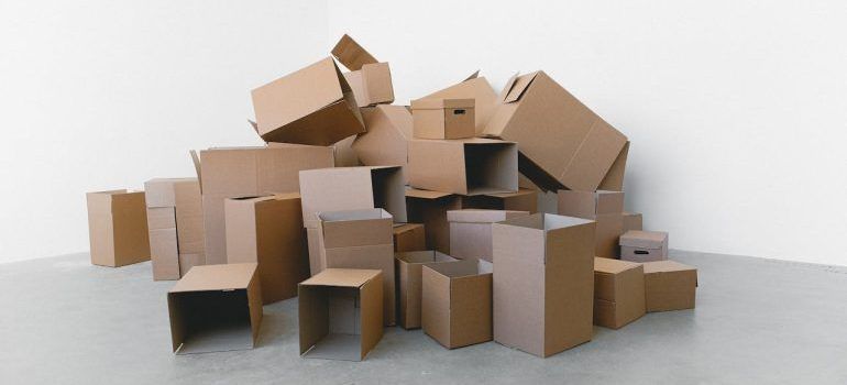 Stack of open cardboard moving boxes on a white floor against a light gray background